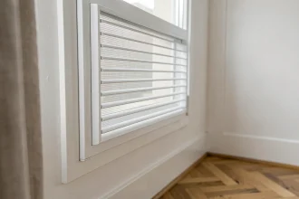 Grille d'aération fenêtre en PVC blanc installée sur un châssis de fenêtre dans un appartement rénové